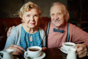 Portrait of retired couple in smart clothes looking at camera in cafe